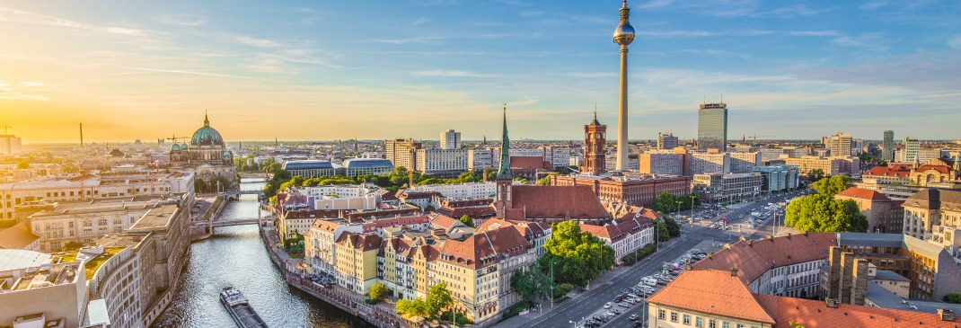 An aerial view of the Berlin skyline with the famous TV tower and Spree river at sunset.