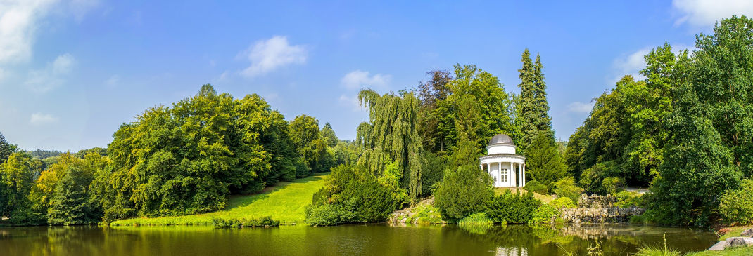 Park in Kassel mit Bäumen und blauem Himmel.