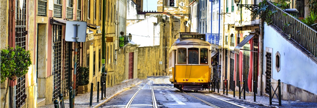 Typical yellow tram travelling down a street in Lisbon