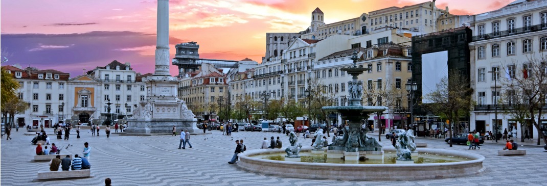 Rossio Square in Lisbon, Portugal filled with people as the sun starts to set