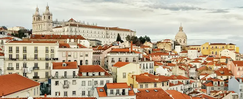 Vista aérea de varios edificios en una ciudad portuguesa, con tejados de teja y un río al fondo.