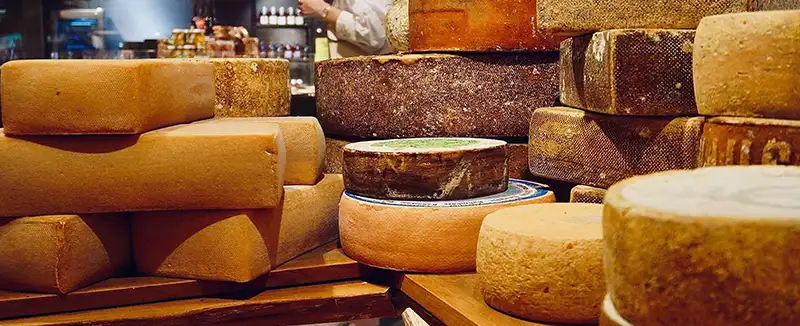 Diverse forme di formaggio impilate tra loro, con evidenza di consistenze e crosta