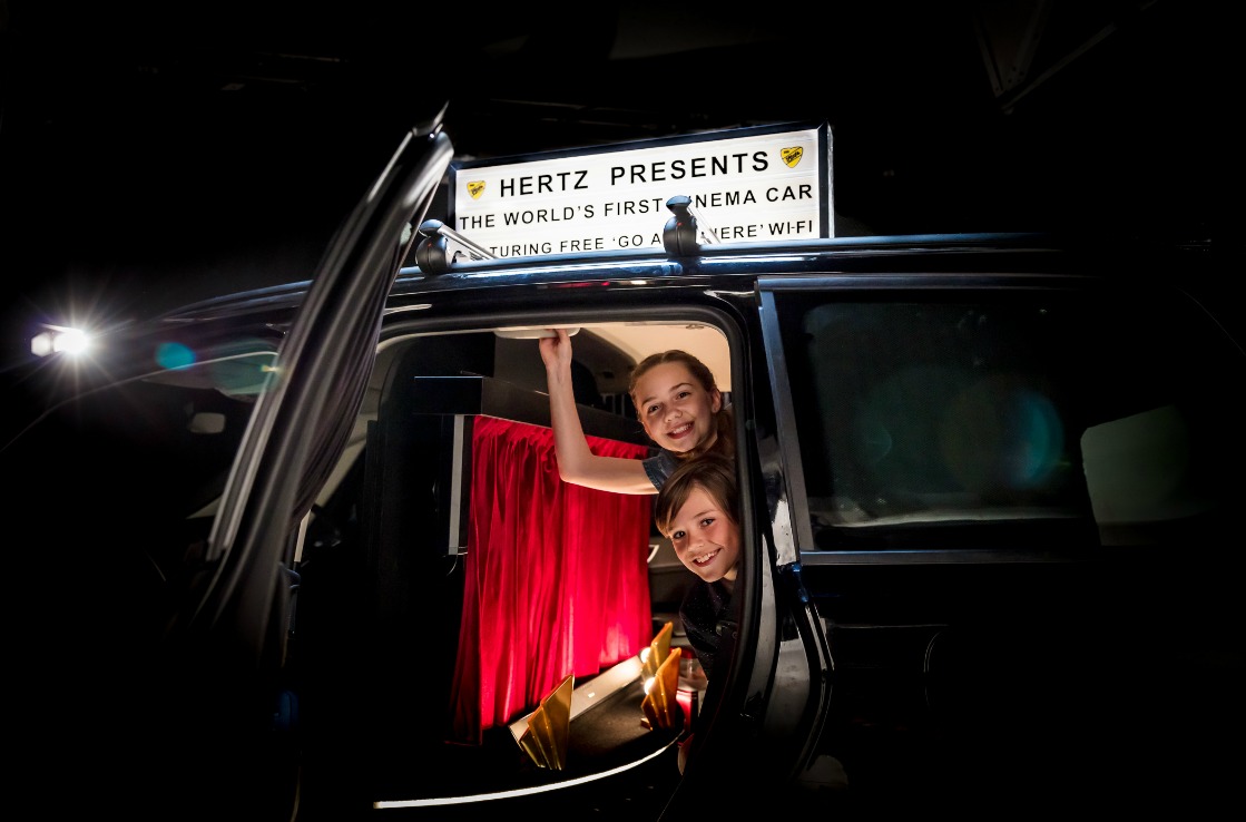 KInder mit Popcorn im Kino-Auto von Hertz