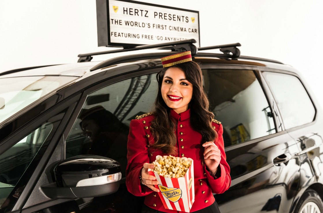 Frau mit Popcorn vor dem Kino-Auto