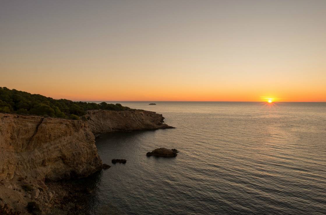 Der Strand Punta Galera auf Ibiza bei Sonnenuntergang.
